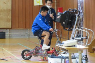 交通安全教室 自転車型のシュミレーターにのる生徒